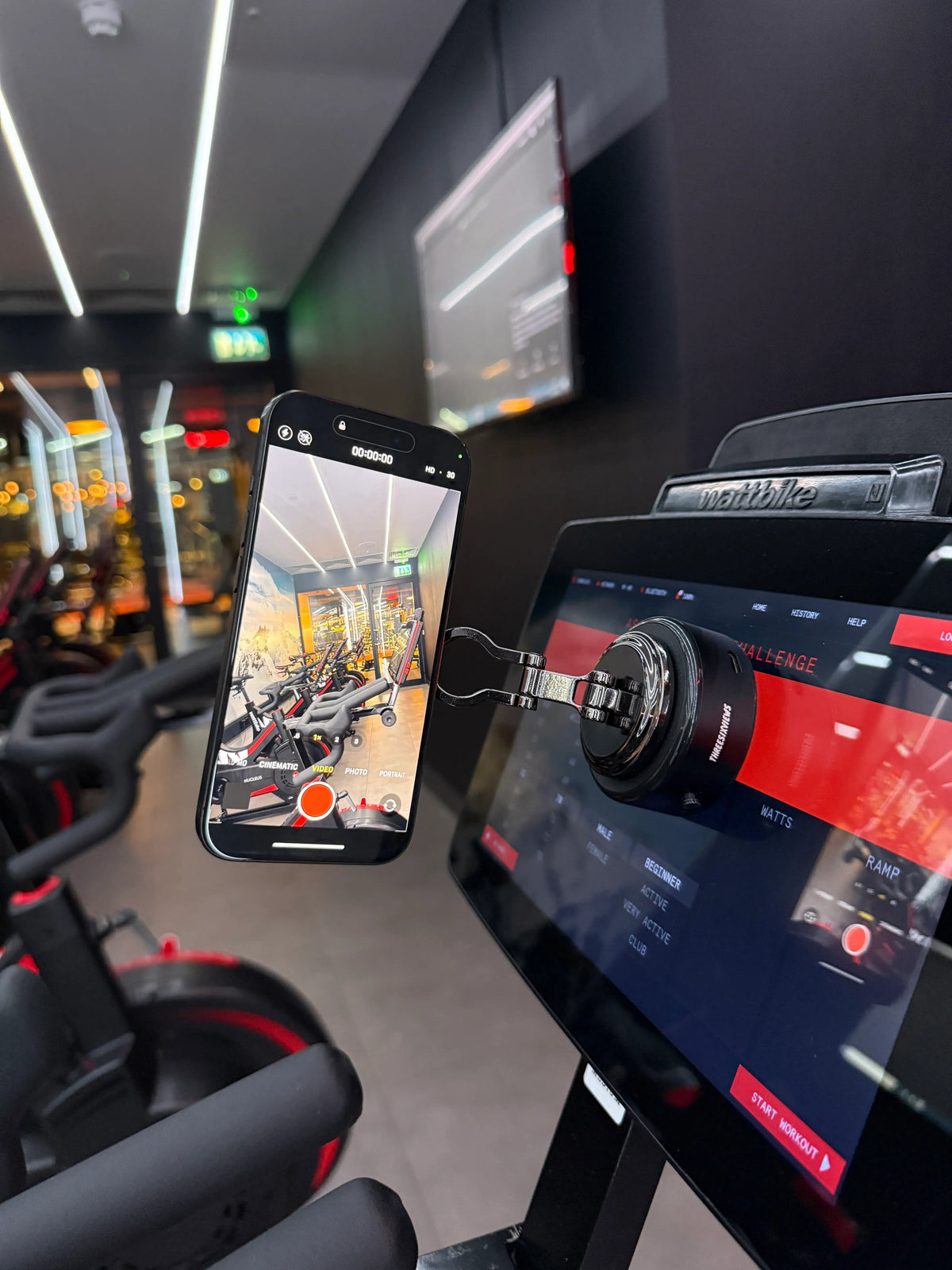 The Smart Vacuum Mount on the glass screen of a studio bike, holding a phone that is recording