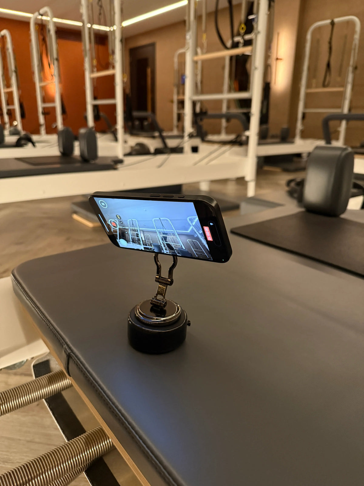 The Smart Vacuum Mount standing on a bench, holding a phone in landscape that is recording